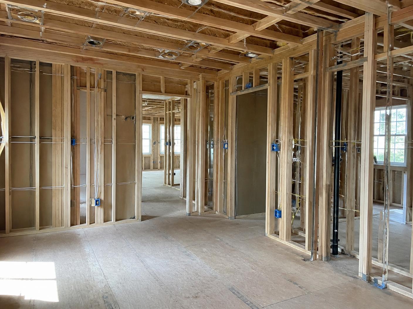 Room during construction with exposed framing, wiring runs, and electrical boxes